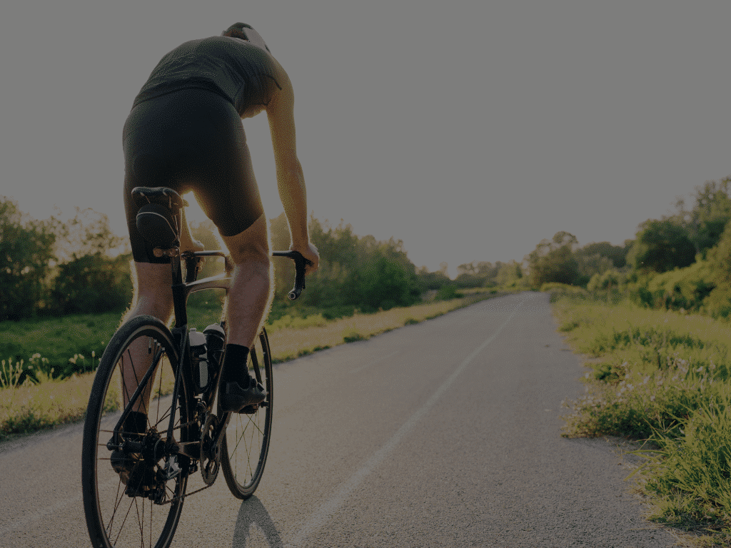 Fietser op een racefiets die op een lege weg fiets.